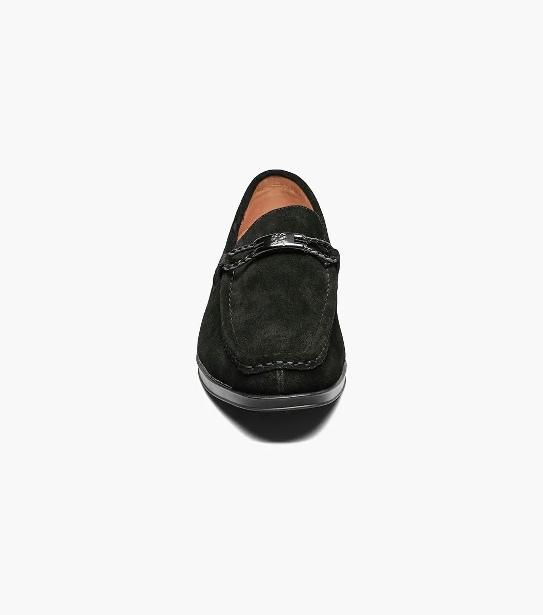 The Stacy Adams NEVILLE Moc Toe Bit Slip On in black suede showcases a metal chain detail on top, accompanied by a slightly elevated heel and stitched accents. Its cushioned insole provides comfort for all-day wear.