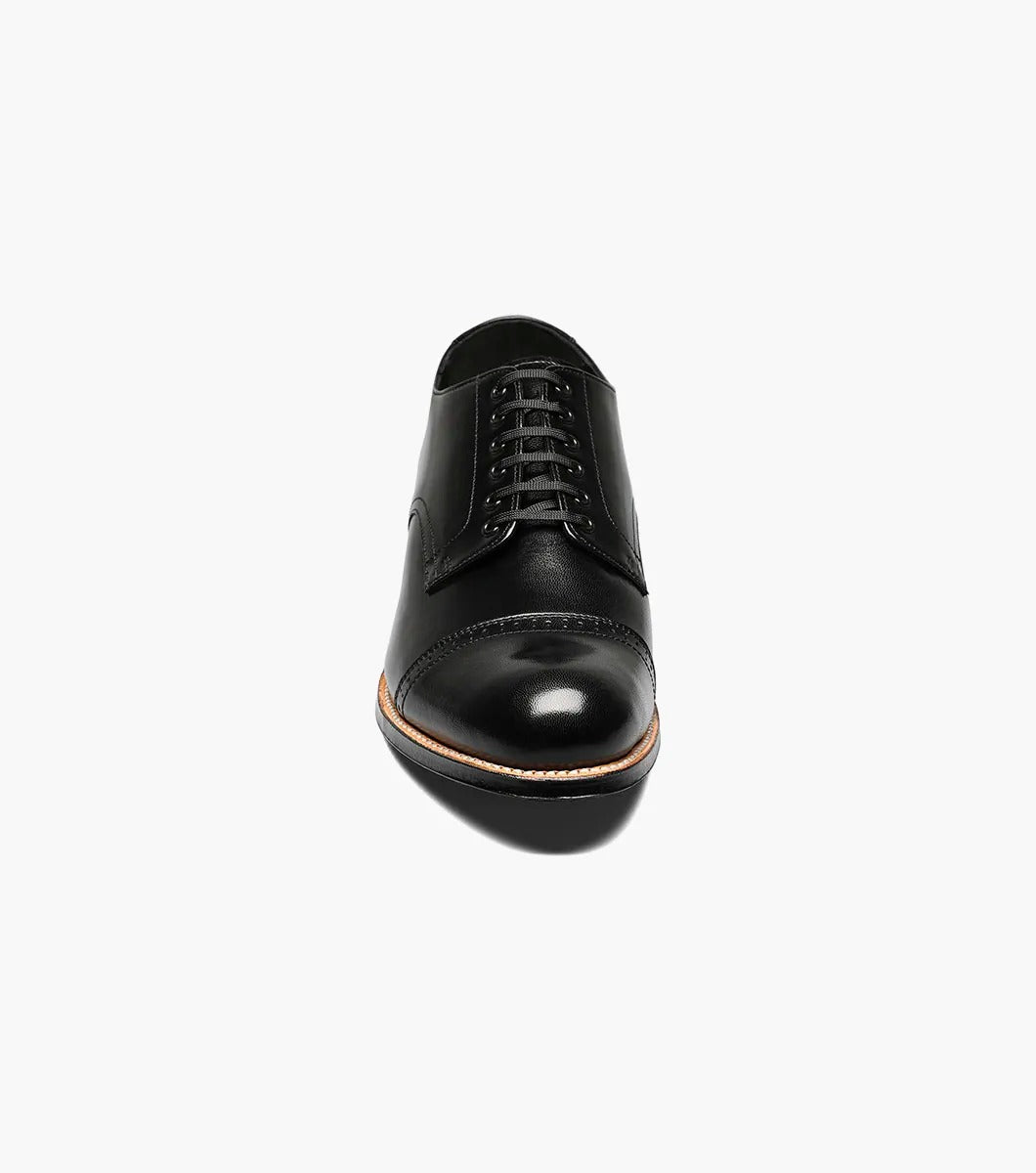 The Stacy Adams MADISON Cap Toe Oxford in black (product code: 00012-01) is a kidskin leather shoe with laces, presented against a pristine white background, and it boasts impeccable Goodyear welt construction for both durability and style.