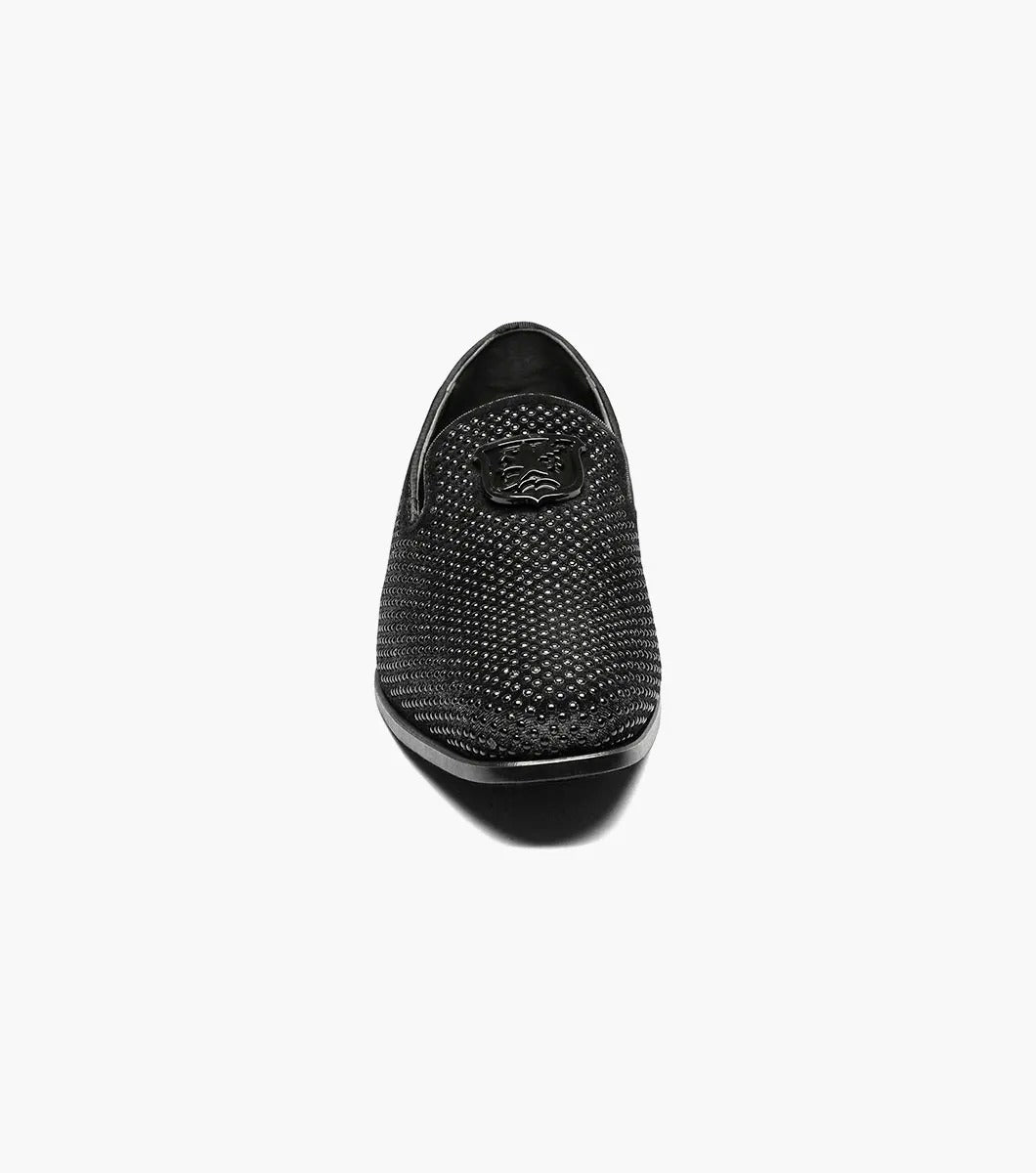 The Stacy Adams - SWAGGER Studded Slip On in black (style 25228-001) features a striking silver emblem, accompanied by a textured design and low heel. These shoes offer a sophisticated touch with the added comfort of memory foam, making them ideal for any occasion.