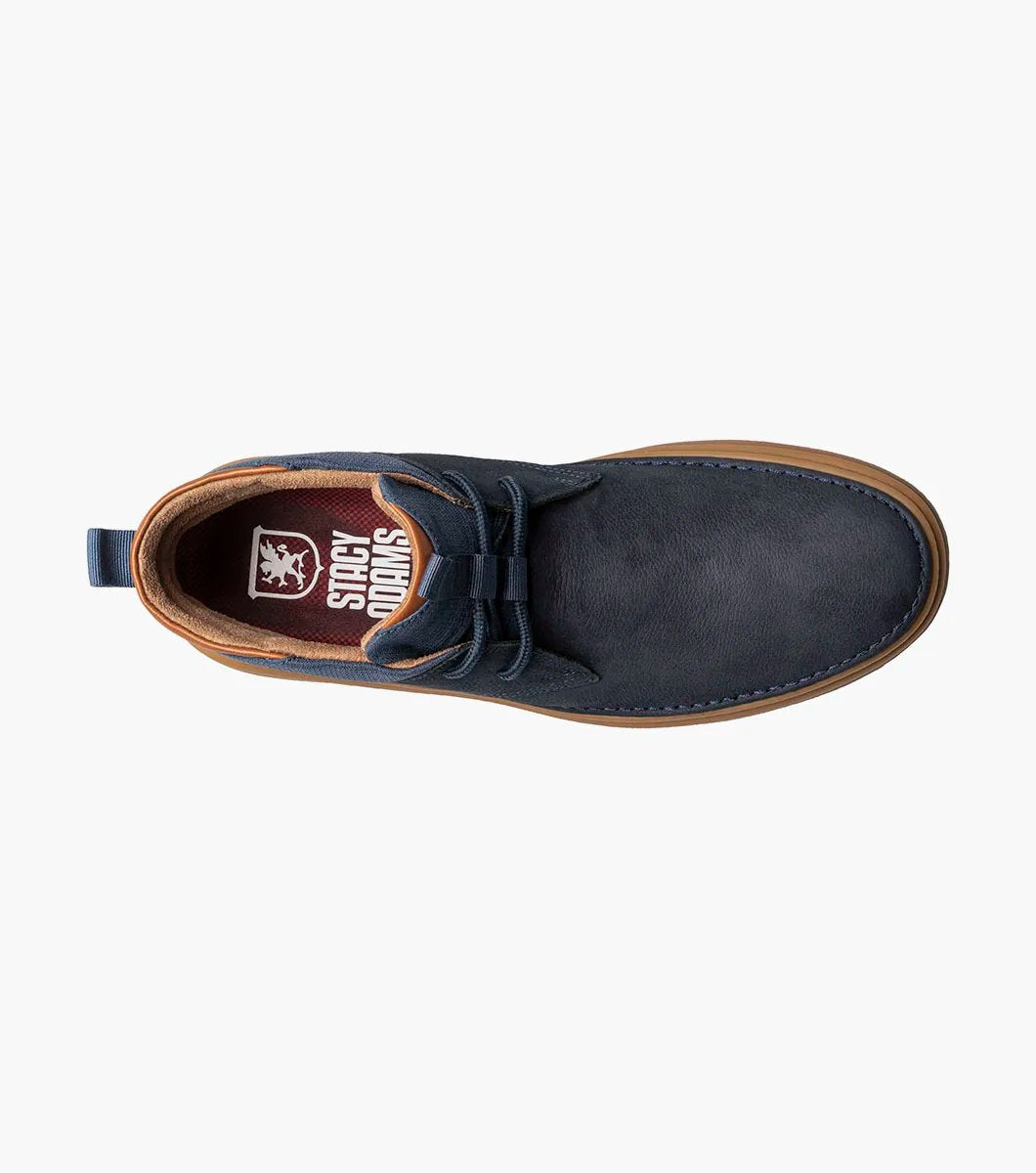 The Stacy Adams DELSON Plain Toe Chukka Boot in Navy showcases a leather upper paired with brown soles and laces, featuring anatomical arch support, set against a white background.