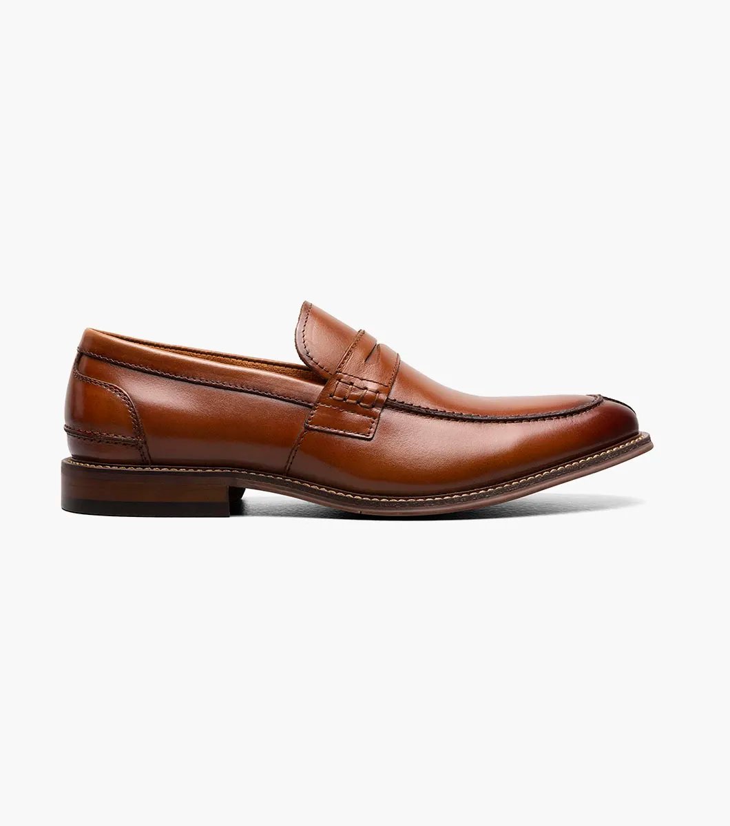 The Stacy Adams MARLOWE Algonquin Moc Toe Penny Slip On in Cognac showcases a sophisticated brown leather design with a low heel and intricate stitching details, equipped with a RedZone Footbed for enhanced comfort.