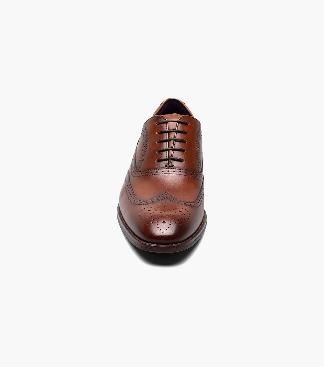 The Stacy Adams KAINE Wingtip Oxford in Cognac, model number 25569-221, from STACY ADAMS, is showcased against a white background, highlighting its intricate stitching and decorative perforations.