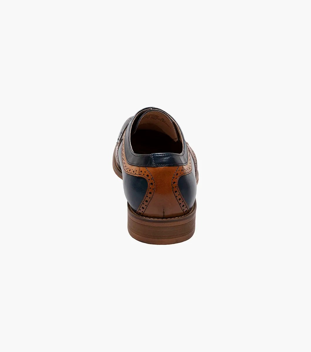 A side view of the Stacy Adams - PALMER Plain Toe Medallion Oxford showcases its navy and brown leather design, complete with decorative perforations and a wooden heel.