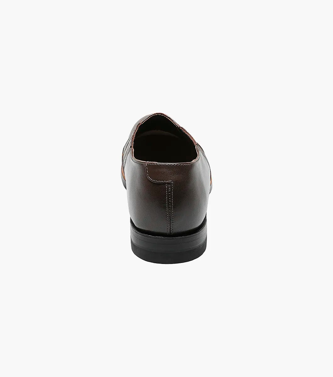 The Stacy Adams - MADISON Cap Toe Slip On in brown is shown in a side profile view against a white background. This shoe features embossed detailing and a low heel, crafted with Goodyear welt construction.