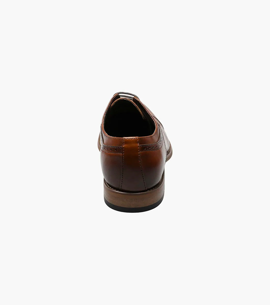 The Stacy Adams - DICKINSON Cap Toe Oxford in Cognac (25066-221) showcases a Leather Upper with decorative perforations, lace-up closure, and Memory Foam for enhanced comfort, all displayed on a white background.