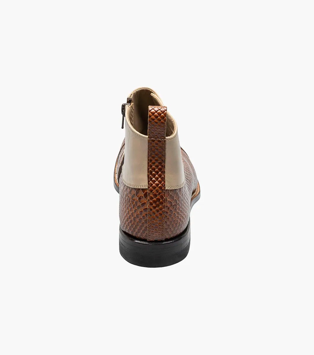 The Stacy Adams MADISON Spectator Spat Cap Toe Demi Boot in Tan Multi showcases a sophisticated design with a smooth kidskin leather upper, textured lower, and black side buttons, complemented by a genuine leather sole for timeless elegance.