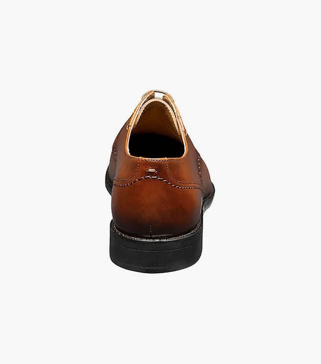 The Stacy Adams BARNETT Cap Toe Oxford in Scotch color, model 20196-232, is a classic brown burnished leather dress shoe with decorative stitching and laces. It features a low heel, smooth sole, and embodies the timeless elegance of a Cap Toe Oxford.