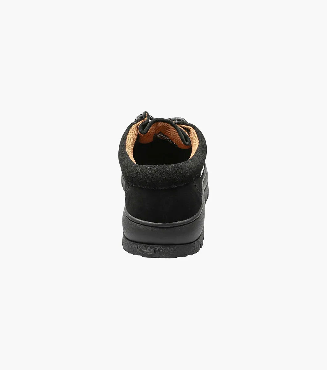 The Stacy Adams DETONATOR Moc Toe Chukka in black suede (63027-11) boasts soft suede material and laces, complemented by its oversized lug sole. Its thick, grooved rubber base enhances both style and comfort against a white background.