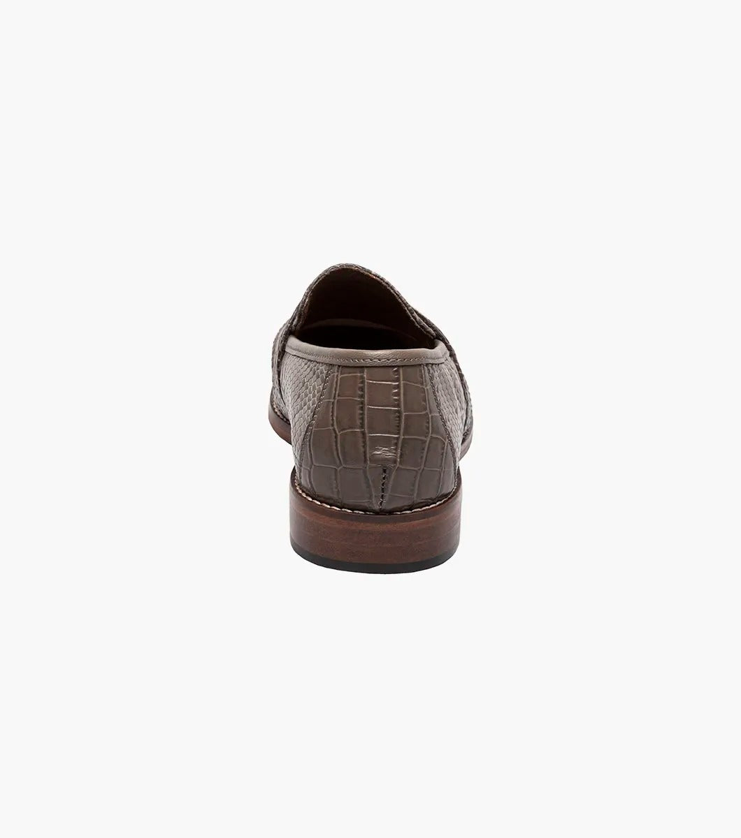 Gray tassel loafer designed by Stacy Adams, made from lizard print leather with dark brown trim and a low heel. It includes a Memory Foam insole for enhanced comfort and is displayed against a plain background.