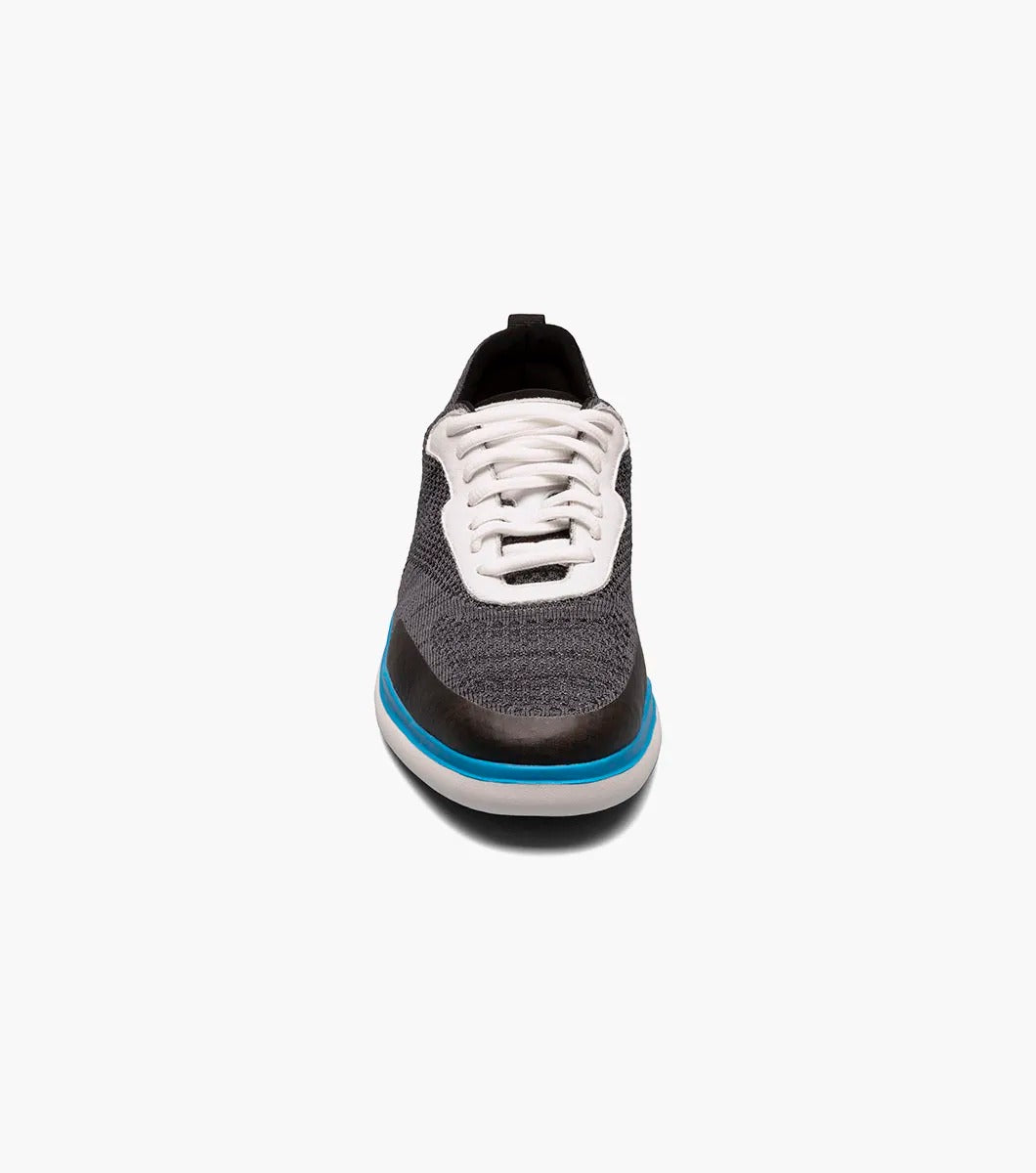 The Stacy Adams - MAXSON Moc Toe Lace Up Sneaker in Black Multi presents a stylish design with a white sole and blue accent, complemented by white laces and a textured mixed material upper for durability. This sneaker also provides anatomical arch support to ensure enhanced comfort with every step.