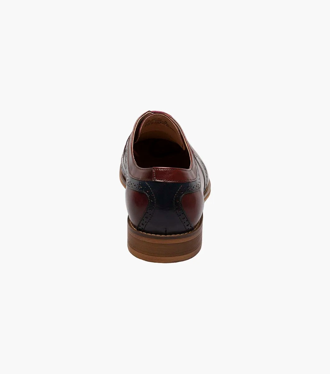 The STACY ADAMS Palmer Plain Toe Medallion Oxford in Burgundy Multi is an elegant men's dress shoe made from luxurious buffalo leather in burgundy and navy, featuring detailed perforations and a traditional wooden sole.