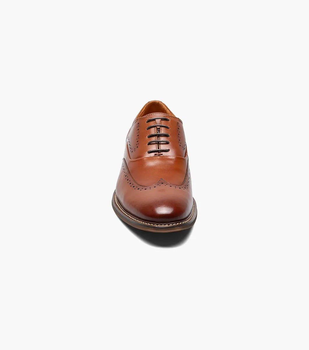 The Stacy Adams - MACARTHUR Wingtip Oxford in Cognac (25489-221) showcases a polished leather design with detailed brogue accents against a white background.