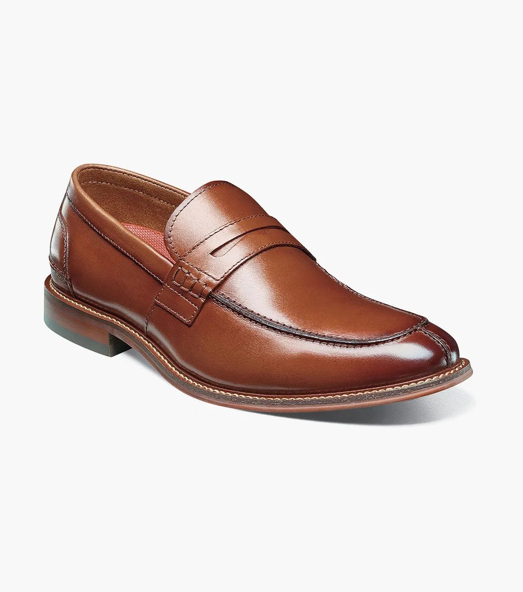 The Stacy Adams MARLOWE Algonquin Moc Toe Penny Slip On in Cognac showcases a sophisticated brown leather design with a low heel and intricate stitching details, equipped with a RedZone Footbed for enhanced comfort.