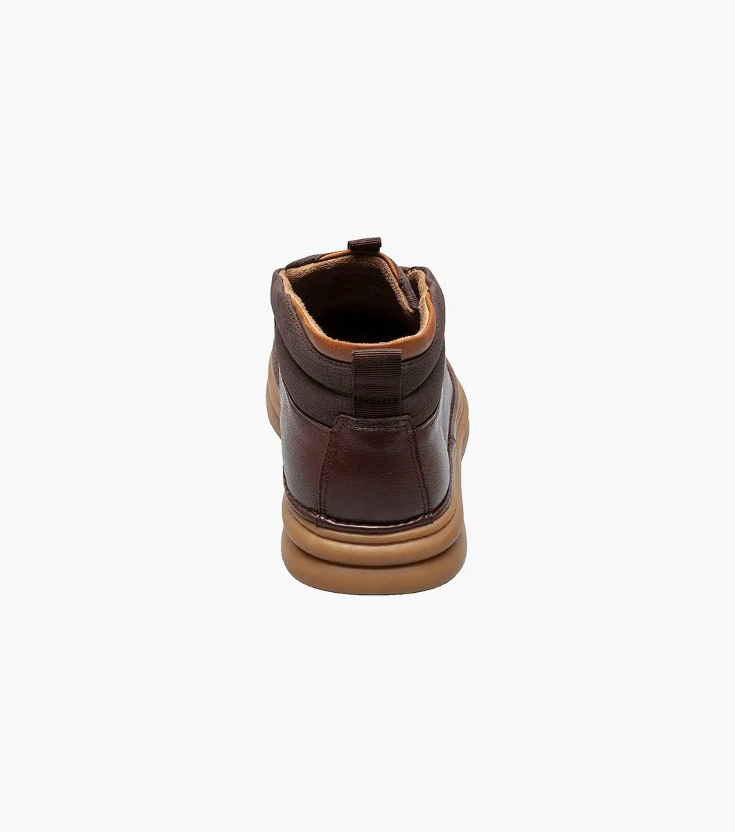 The Stacy Adams DELSON Plain Toe Chukka Boot in Chocolate, style number 25556-202, features a brown leather design with a rounded toe, lace-up front, and a cushioned brown sole with anatomical arch support, all presented against a white background.