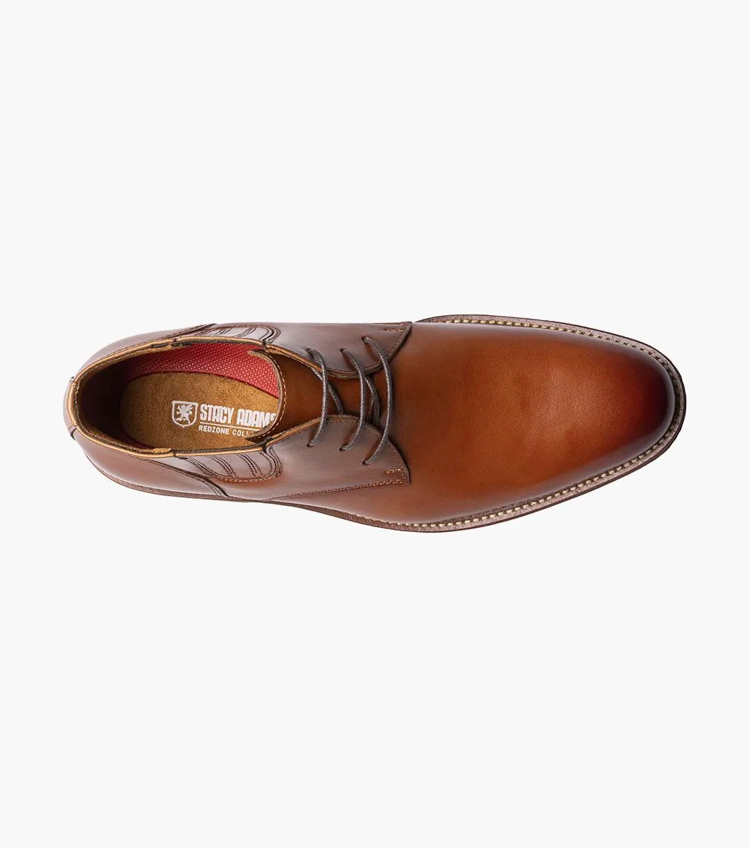 The Stacy Adams Maxwell Plain Toe Chukka Boot in Cognac features a sophisticated leather design with three eyelets, detailed stitching, and a versatile low heel, making it ideal for both dressy and casual events.