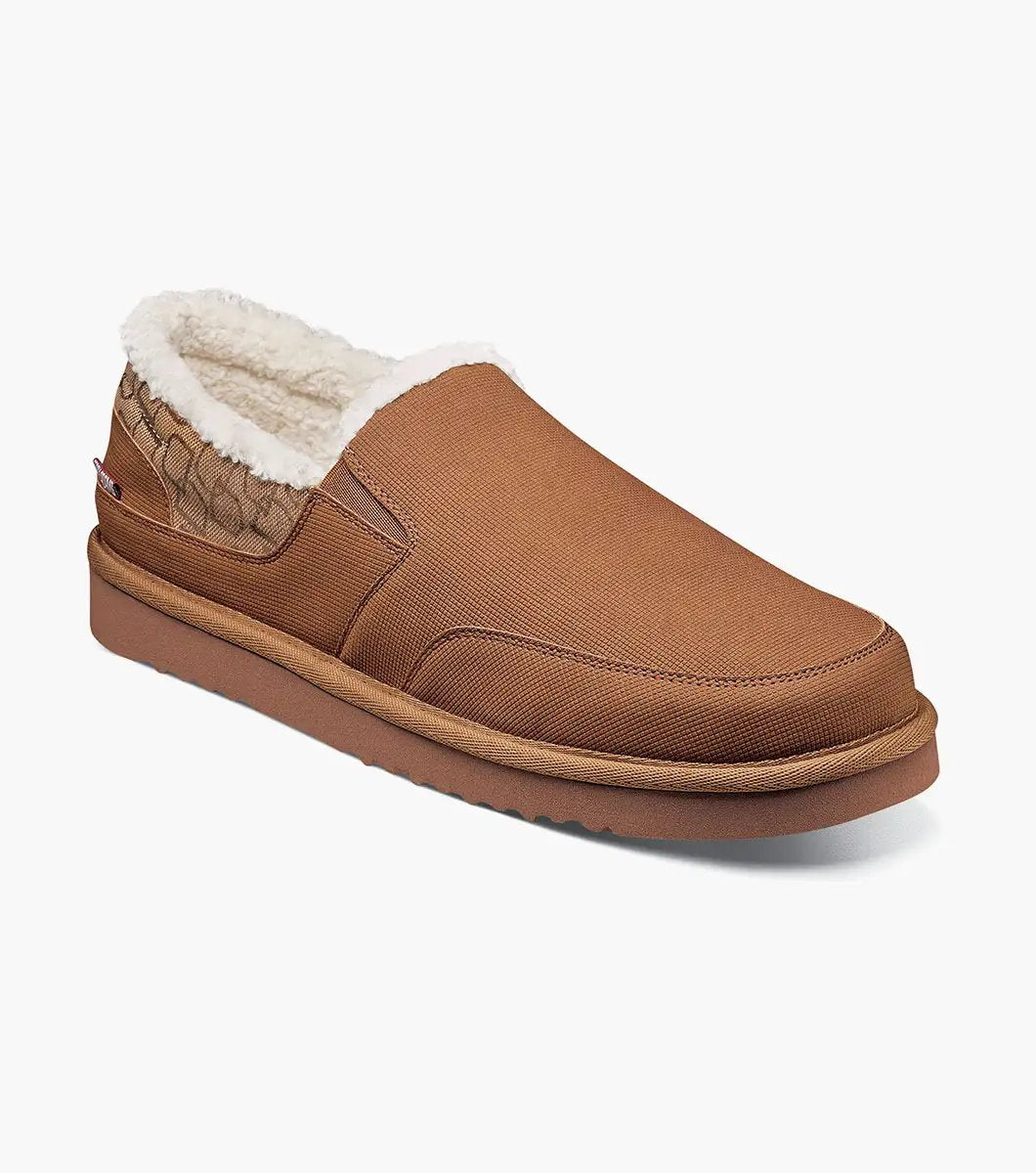 The Stacy Adams - COZE Moc Toe Slip On - Tan Multi - 25558-238, from STACY ADAMS, boasts a textured fabric exterior and soft faux shearling lining. It features a cushioned insole and a brown rubber sole.