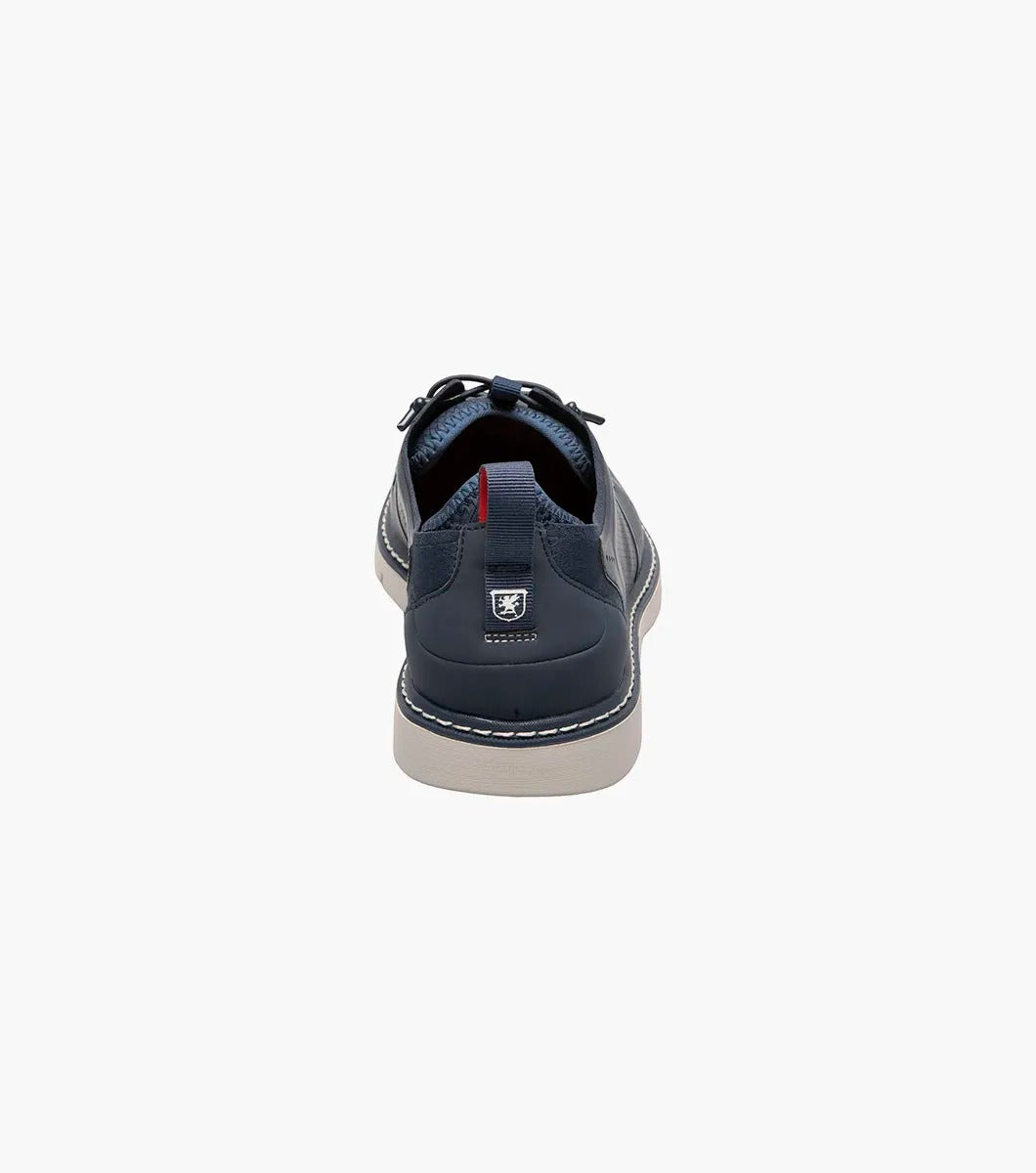 The Stacy Adams SYNCHRO Plain Toe Elastic Lace Up shoe in navy boasts a perforated pattern and a red pull tab, complemented by a light gray sole. It is designed with the RedZone removable footbed to provide anatomical arch support.