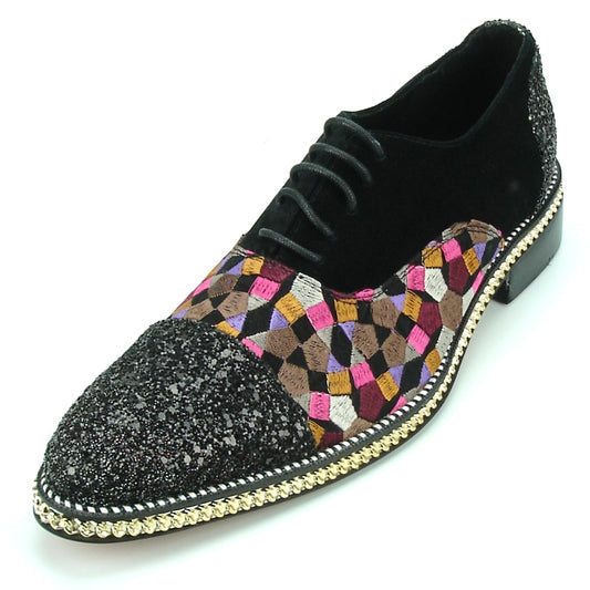 The FI-7125 Black Multi by Fiesso, from the Aurelio Garcia collection, is a stylish black fashion shoe featuring a glittery toe and adorned with a colorful geometric pattern on the sides. It is complemented by an elegant gold chain detail around the sole. The suede upper and cushioned insole provide both style and comfort with every step.