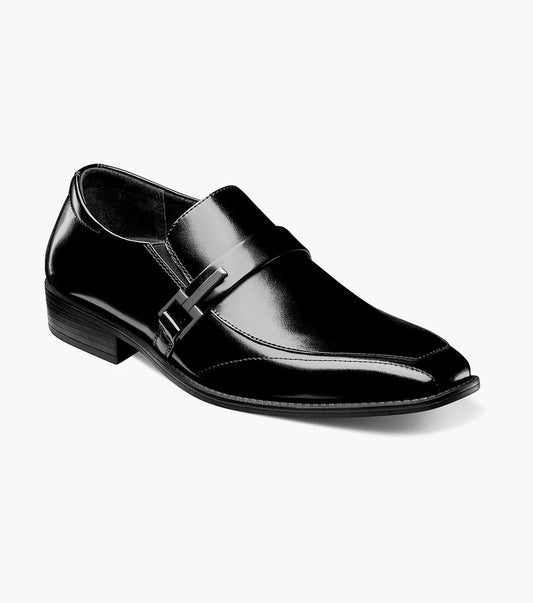 The Stacy Adams - ABRAM Moc Toe Bit Slip On, product number 20186-001, is a black leather dress shoe with a buckle detail, low heel, and cushioned insole for enhanced comfort. It is presented against a plain white background.