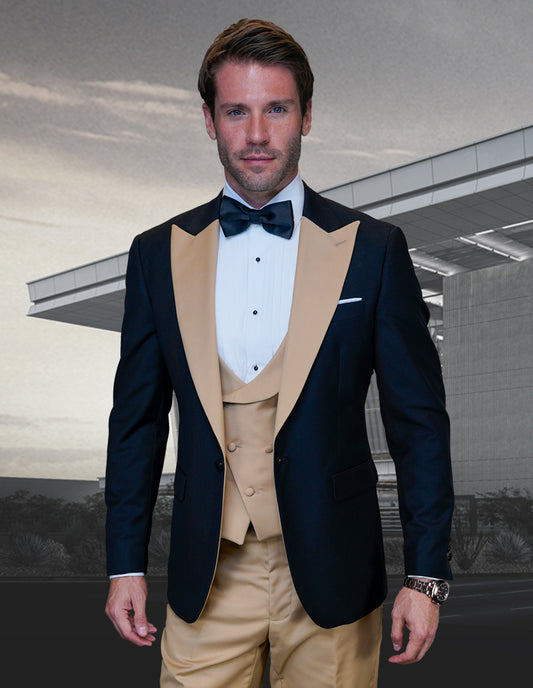 A man dressed in the STATEMENT CLOTHING | ARYA-CHAMPAGNE tuxedo suit from Statement Clothing, crafted from fine Italian fabric in black and gold, paired with a white shirt and bow tie, stands in front of a modern building.