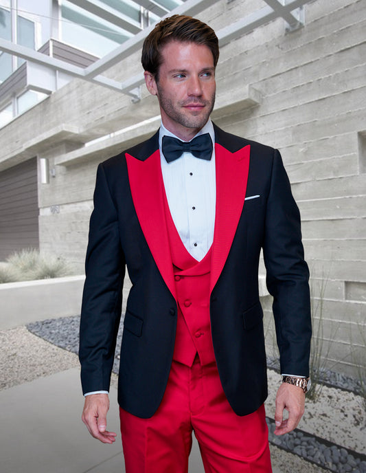 A man stands outdoors in a stylish ARYA-RED tuxedo suit with a bow tie from Statement Clothing, exuding sophistication in a modern architectural setting and showcasing the elegance of Italian fabric.