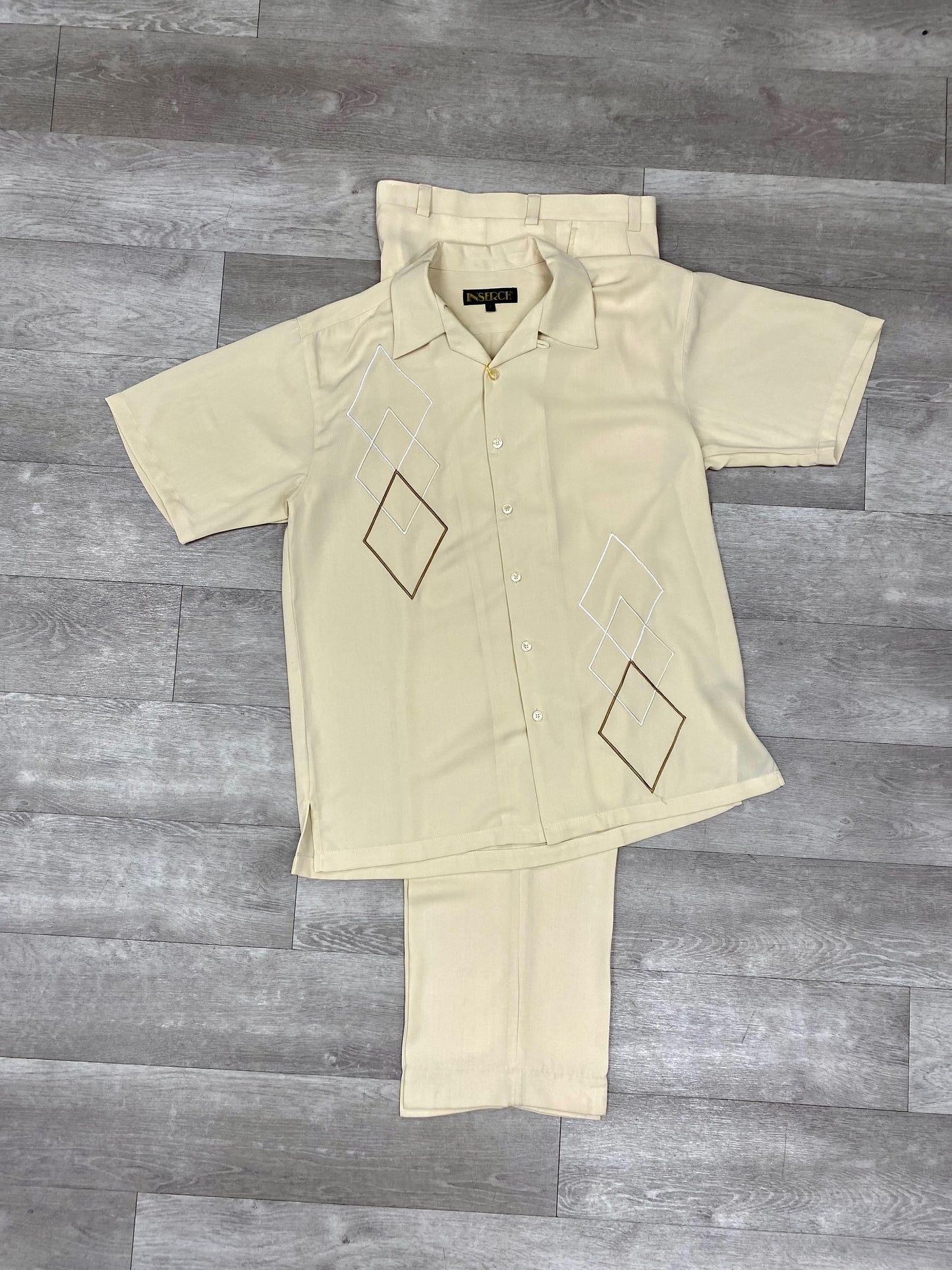 The Inserch 2pc 9356 Beige set, crafted from soft microfiber with geometric designs, features a beige short-sleeve shirt and pant ensemble elegantly displayed on a wooden floor. This model introduces a modern touch of elegance to any wardrobe.