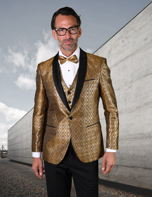 Wearing the STATEMENT CLOTHING | BELAGIO21-GOLD from Statement Clothing, a man in glasses sports a gold patterned suit complete with a gold bow tie and slim fit flat front pants, standing outdoors against a concrete wall.