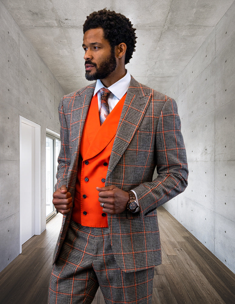 The man in a tailored statement plaid suit crafted from fine Italian wool stands in a concrete hallway, his Benson-Coral vest adding a touch of flair as he gazes to the side.