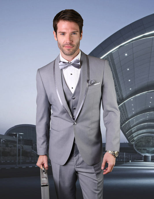 A man confidently stands in front of a modern, curved architectural structure, dressed in the STATEMENT CLOTHING | CAESAR-GREY tailored fit suit and bow tie from Statement Clothing.