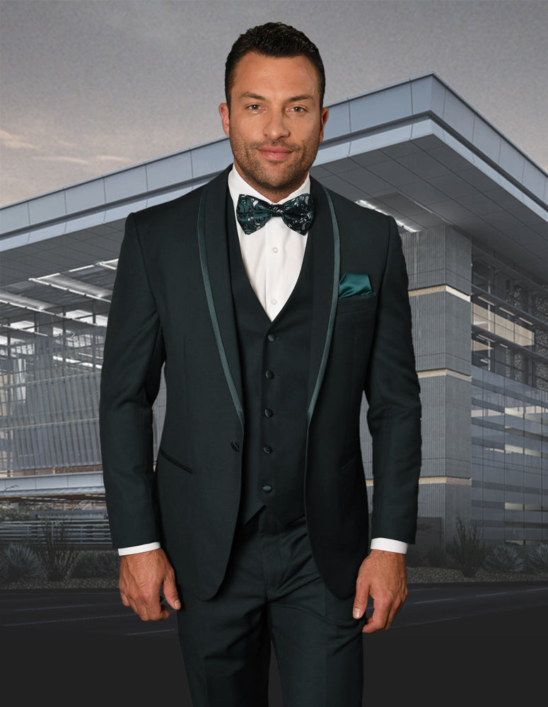 A man in a tailored fit STATEMENT CLOTHING | CAESAR-HUNTER dark suit and matching bow tie stands in front of a modern building with glass and metal architecture.