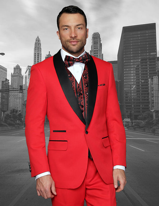 A man in a vibrant modern fit tuxedo from Statement Clothing's "CAPRI-RED" collection, featuring black lapels and a patterned bow tie, stands proudly against a grayscale cityscape background.