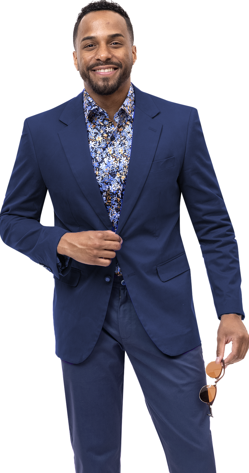 A man in a EJ Samuel Midnight Solid Chino Blazer and a floral shirt smiles while holding sunglasses, displaying an impeccable sense of style.