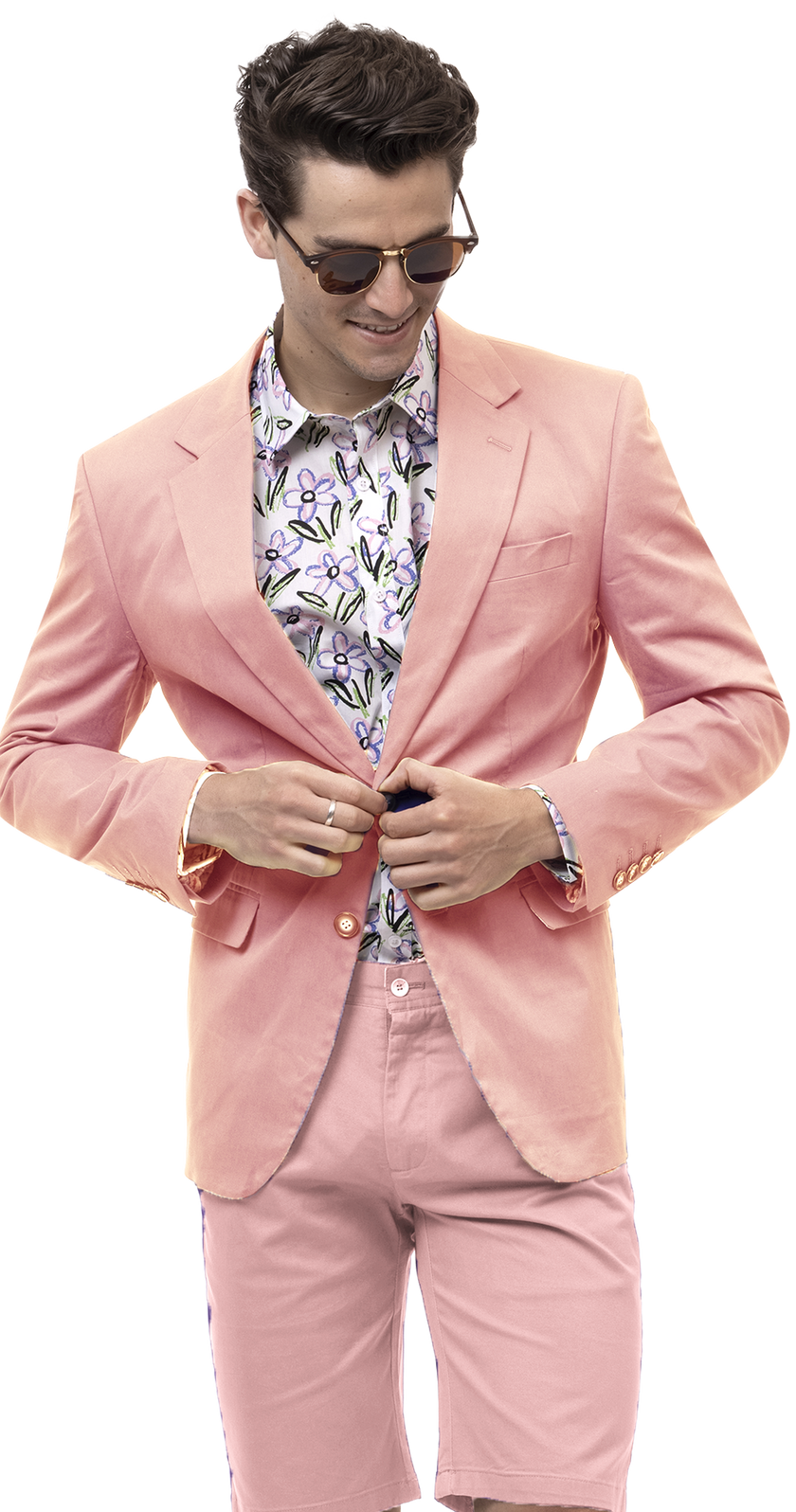 A person in the EJ Samuel Pink Solid Chino Blazer CHJ01 and a floral shirt, wearing sunglasses, looks down while adjusting their solid blazer with confident ease.