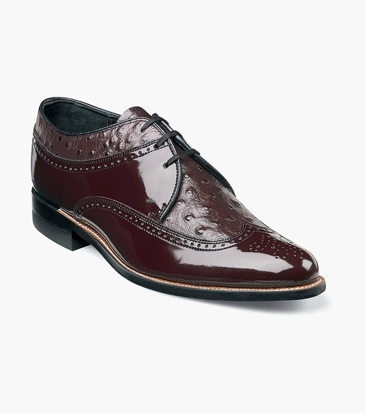 A single polished DAYTON Ostrich Wingtip Oxford shoe by STACY ADAMS in burgundy leather, featuring black laces, decorative perforations, a low stacked heel, and Goodyear welted construction.