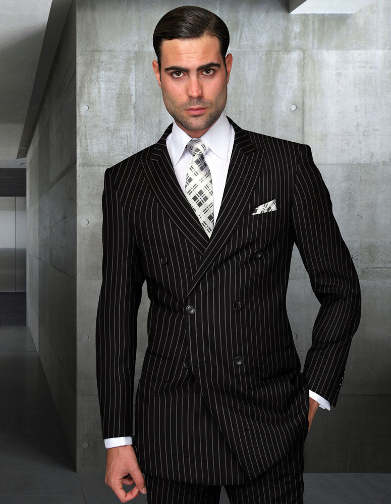 A man in a Statement Clothing DB-ZARELLI-BLACK suit and patterned tie stands in a modern hallway with concrete walls, looking directly at the camera.