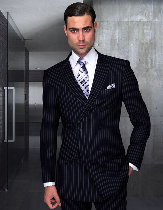 A man dressed in the DB-ZARELLI-NAVY double-breasted pinstripe suit from Statement Clothing, paired with a patterned tie, stands in a modern hallway with concrete walls.