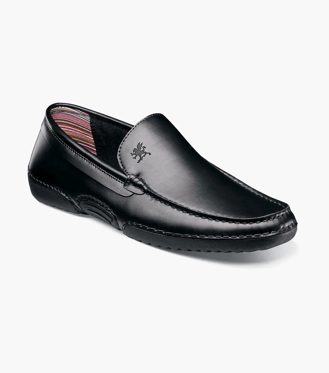 A Stacy Adams DEL Moc Toe Loafer in black leather, featuring a discreet logo on the side. The interior is lined with a striped pattern, providing both style and comfort.