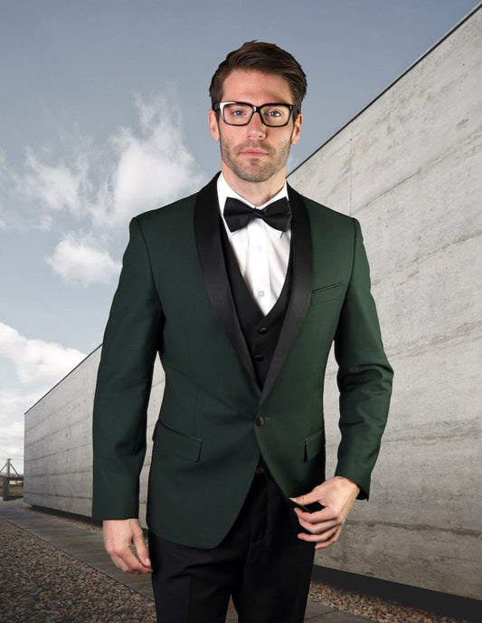 A man in glasses stands outdoors against a concrete wall and cloudy sky, dressed in the ENCORE-HUNTER tailored fit tuxedo with a matching bow tie by Statement Clothing.