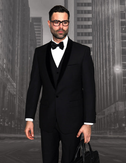 A man in the STATEMENT CLOTHING | ENCORE-V-BLACK tuxedo, featuring a velvet lapel and flat front pants by Statement Clothing, stands on a city street holding a briefcase.