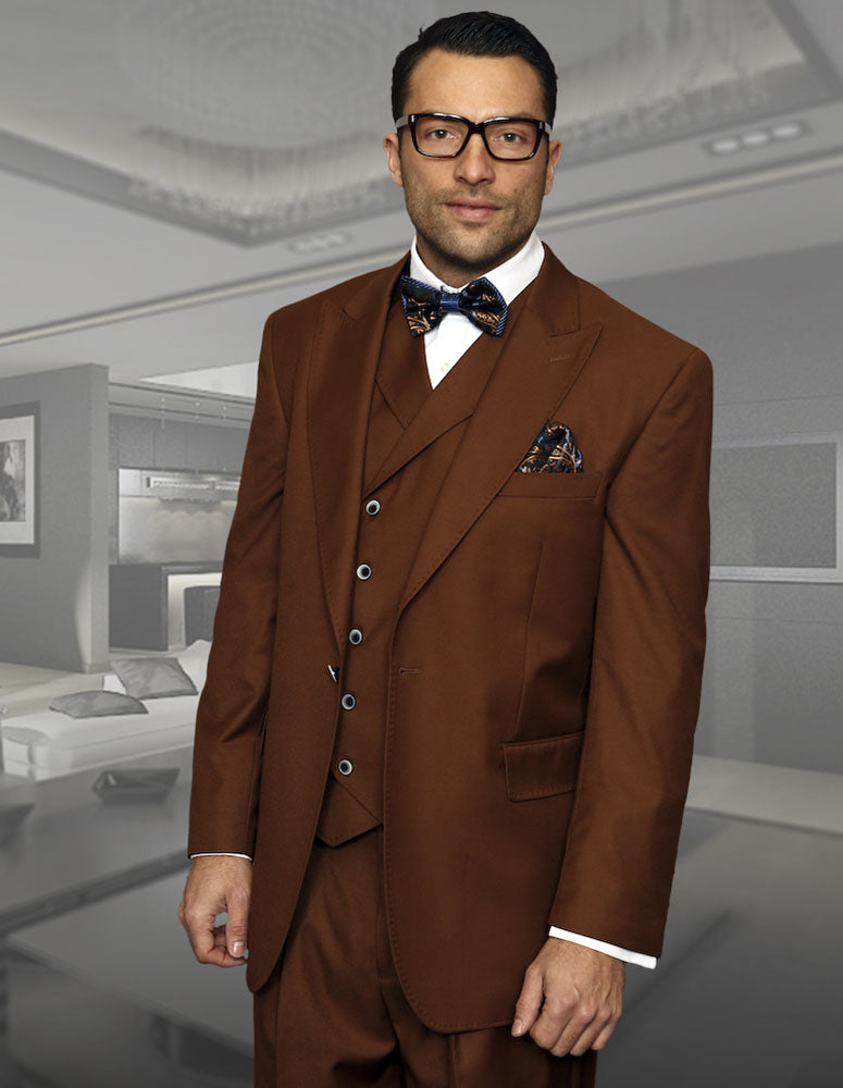 A man elegantly stands in a modern living room, dressed in the STATEMENT CLOTHING | FLORENCE-COPPER Italian wool three-piece suit from Statement Clothing, complete with a bow tie.