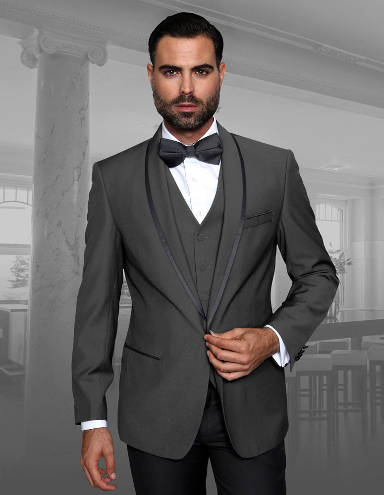 A man in the GENOVA-CHARCOAL suit by Statement Clothing, complete with a tailored fit and bow tie, stands in a room with columns and large windows.