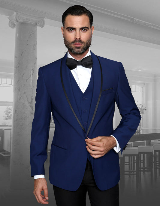 A man wearing the GENOVA-SAPPHIRE tailored tuxedo by Statement Clothing, paired with a black bow tie, stands in a stylish room featuring neutral decor.