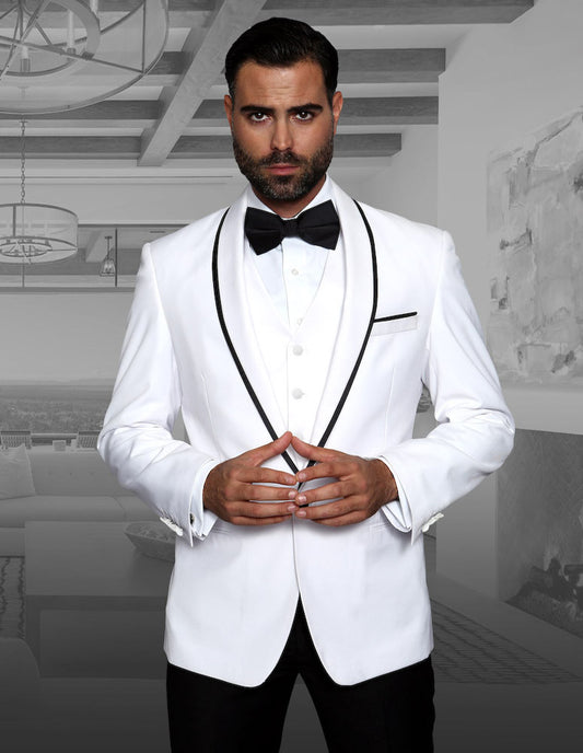 A man in a crisp STATEMENT CLOTHING | GENOVA-WHITE tuxedo from Statement Clothing, complete with a black bow tie, stands indoors demonstrating the tailored fit of his suit while holding his hands together.