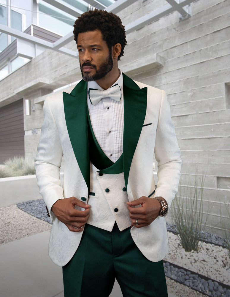 A man in the chic and contemporary STATEMENT CLOTHING | HILTON-HUNTER green and white tuxedo suit by Statement Clothing, complete with a bow tie, stands outdoors in front of a modern building.