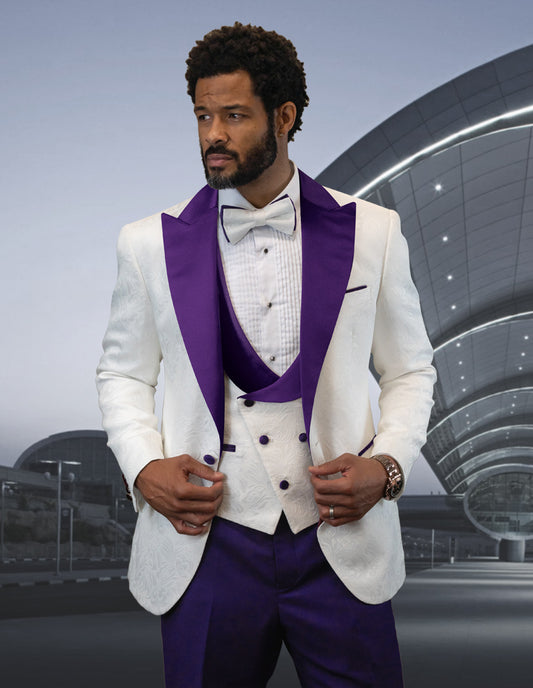 A man in a STATEMENT CLOTHING | HILTON-PURPLE modern fit tuxedo suit stands outside a sleek building with a curved roof.