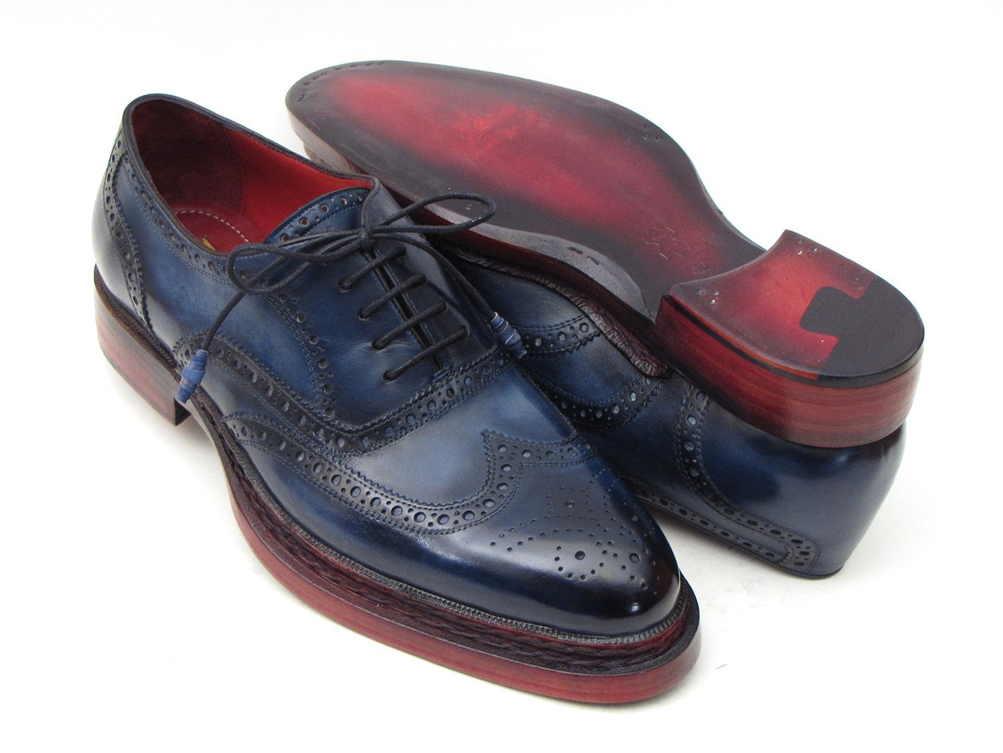 Introducing the Paul Parkman Triple Leather Sole Navy Wingtip Oxfords - 027TRPNVY. These navy wingtip oxfords by Paul Parkman showcase exquisite craftsmanship with intricate perforations and striking red-brown soles. Hand-painted to perfection, they feature a Goodyear welted construction for enduring elegance and durability.