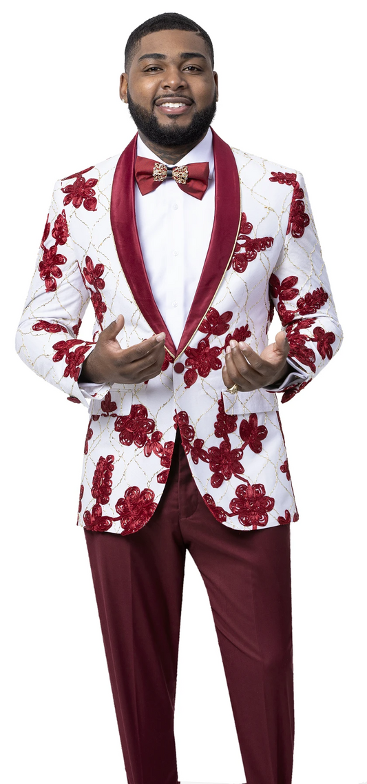 The individual stands elegantly against a white backdrop, wearing an EJ Samuel creation: the Burgundy Blazer J101 with vibrant floral patterns, completed by a striking red bow tie, effortlessly exuding confidence and grace.