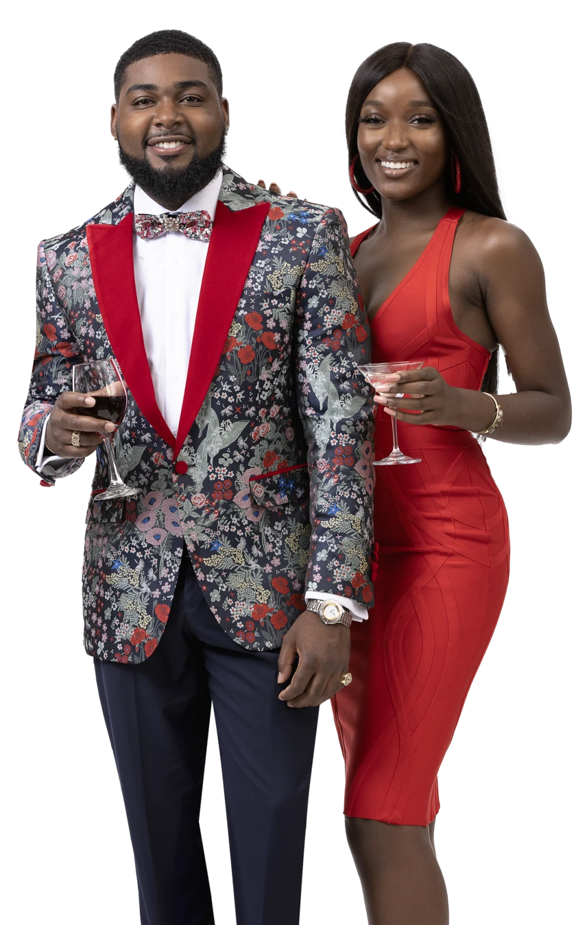 A man wearing an EJ Samuel Blue/Red Blazer J118 and a woman adorned with a red velvet lapel smile at the camera, wine glasses in hand, capturing the elegance of the moment.