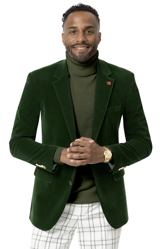 A person wearing the EJ Samuel Green Velvet Blazer J134 with gold buttons, paired with an olive turtleneck and plaid pants, smiles while standing with hands clasped.