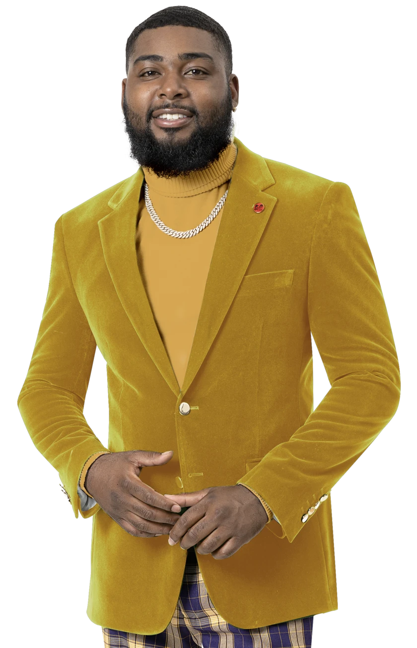 Dressed in the EJ Samuel Mustard Velvet Blazer J134 from the renowned brand EJ SAMUEL, a person wearing a turtleneck embellished with gold buttons smiles warmly, their look perfectly complemented by a stylish necklace.